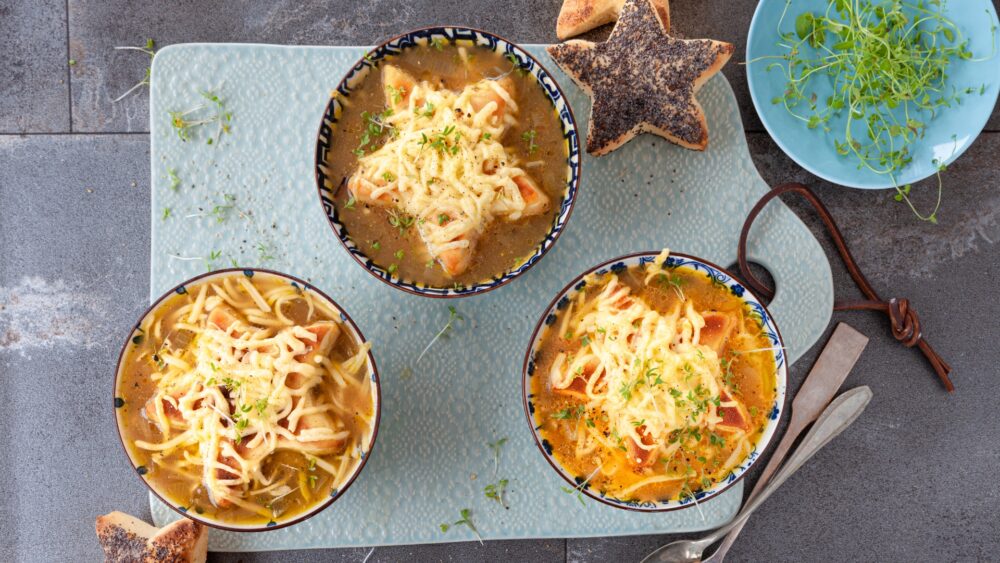 Three crocks of french onion soup with a bread in the shape of a star and cheese on top.