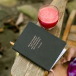 a person sitting to journal with a fresh, organic juice at Blue Osa Yoga Retreat & Spa.