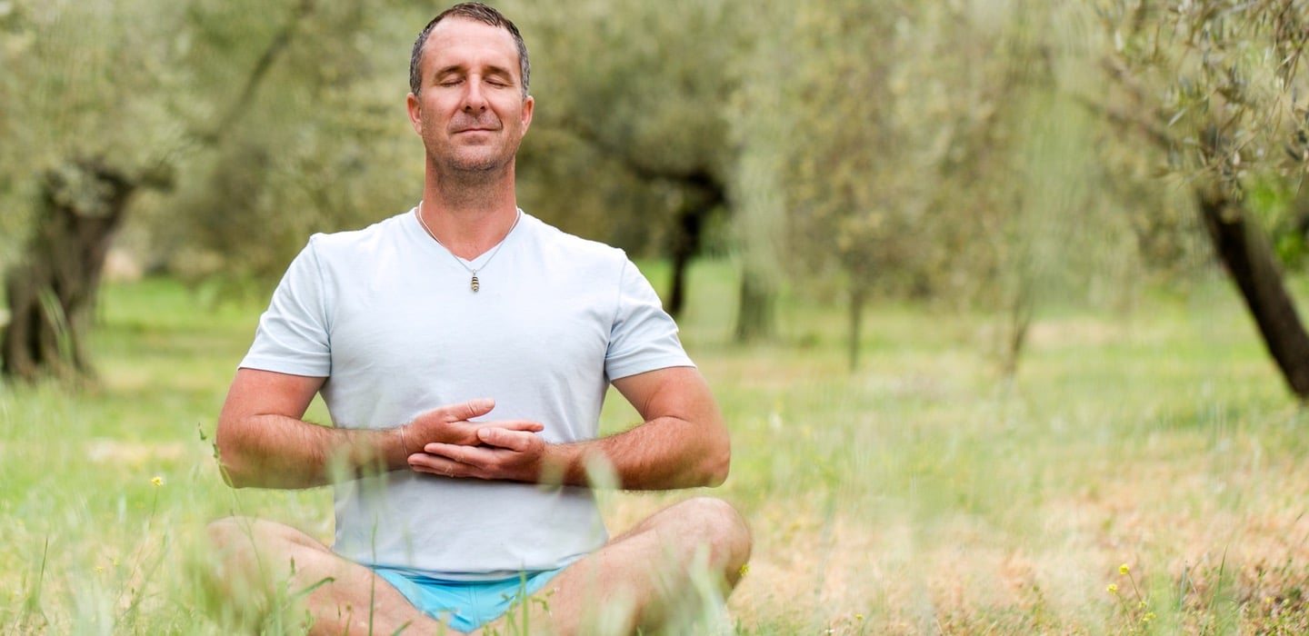 Yogi Aaron meditating in a grassy area at Blue Osa Yoga Retreat & Spa