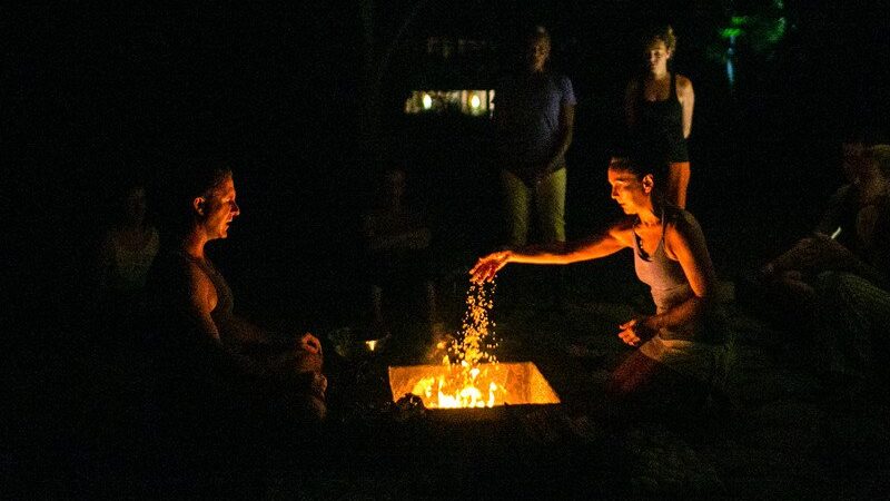 Woman throwing something into a fire during a ceremony at Blue Osa yoga teacher training in Costa Rica.