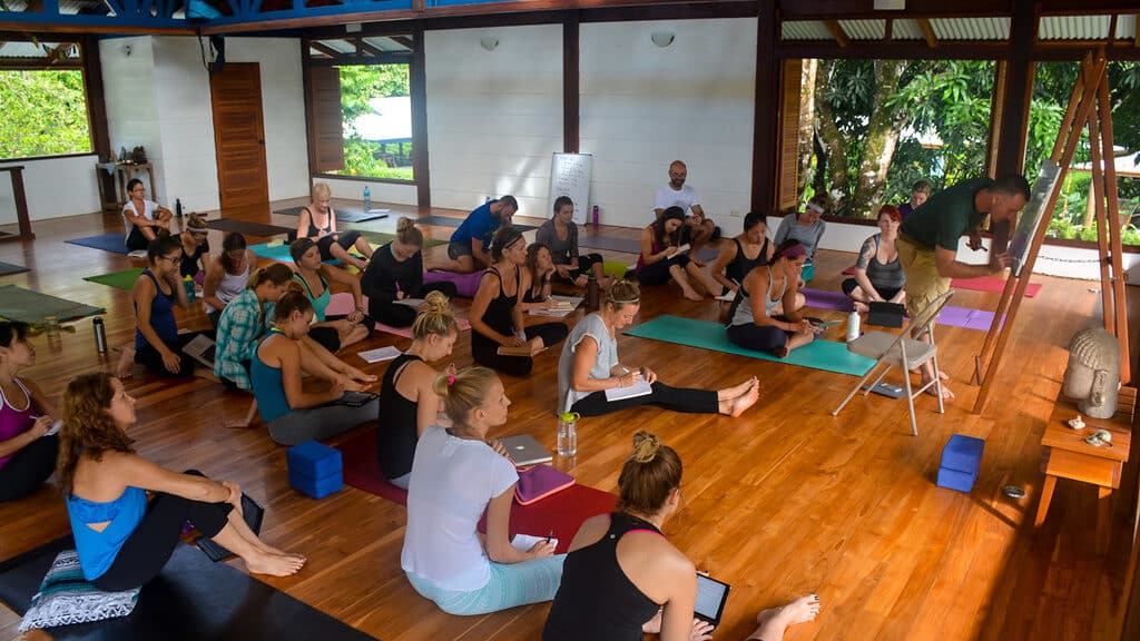 Yoga students sitting on their mats taking notes in Blue Osa's yoga shala in Costa Rica at a YTT.