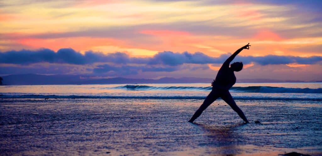 man on beach yoga at sunrise